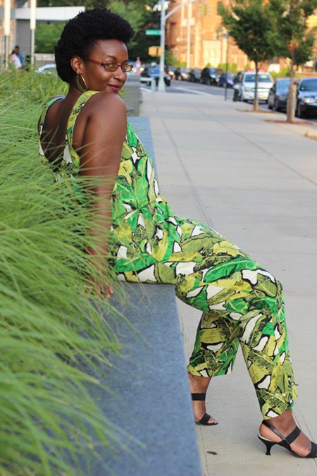 Dark skinned Caribbean & African American woman wearing a green TopShop jumpsuit with a banana leaf design pattern