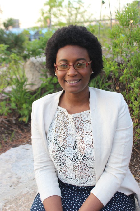 Potrait of a dark skinned Caribbean & African American young woman with an afro hairstyle wearing a lace top and pearl earrings and pearl earrings